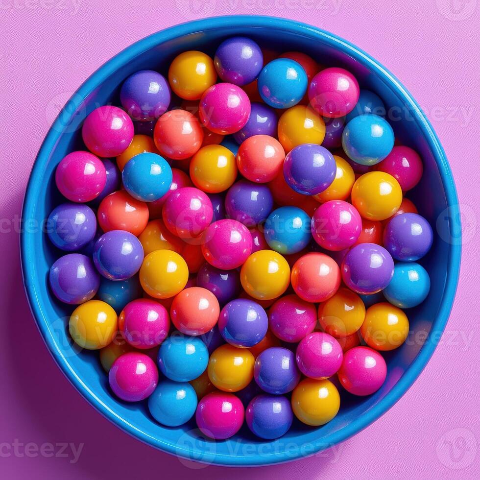 A bowl full of colorful balls on a pink background photo