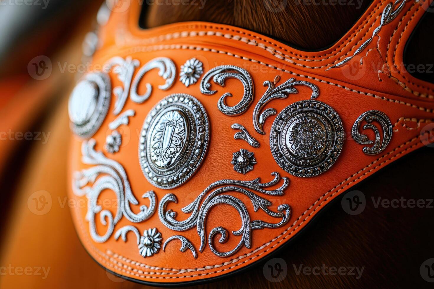 A close up of a horse's saddle with silver and orange decorations photo