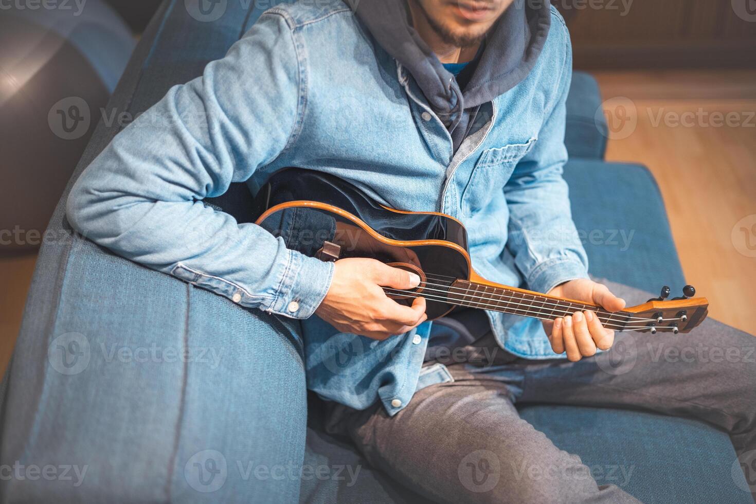 He taps the ukulele top to mark the beat between strums. Blue jacket photo