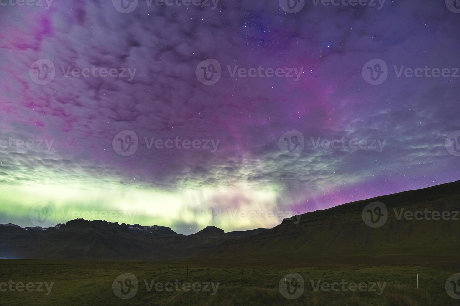 Undercurrents of aurora borealis flow above stony summits. photo