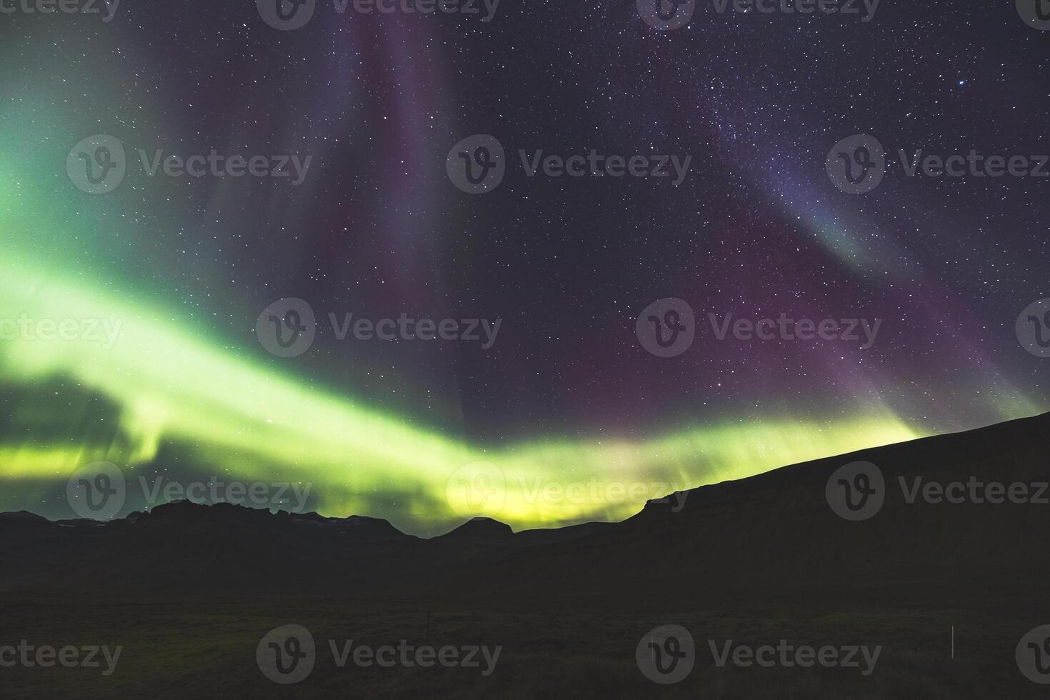 Pulsing green veils sweep across the mountain backdrop. photo