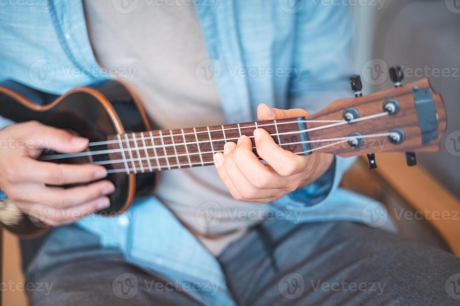 He strums a reggae rhythm on his four-string instrument. photo