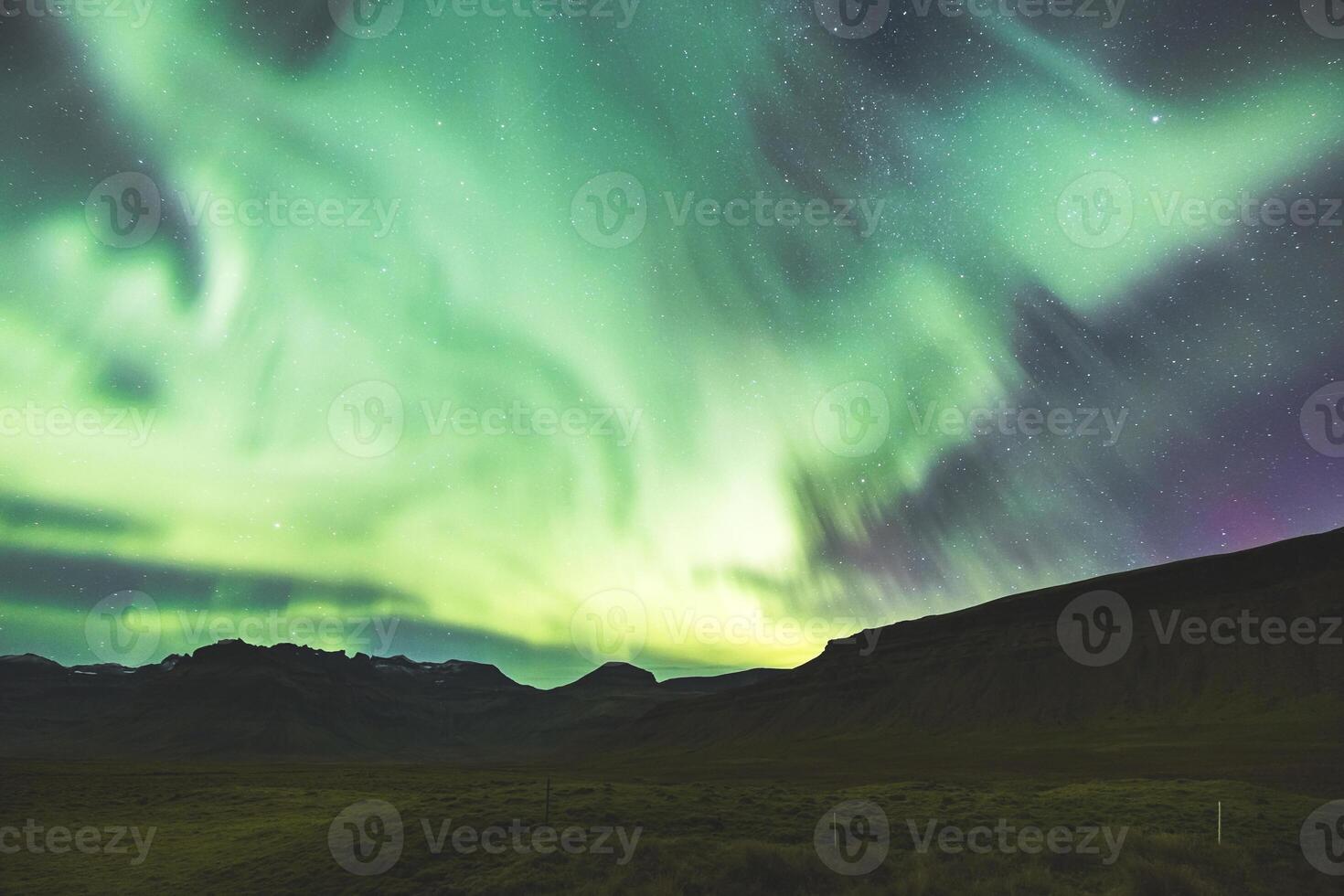 Flickering aurora streams trace the mountain outline. photo