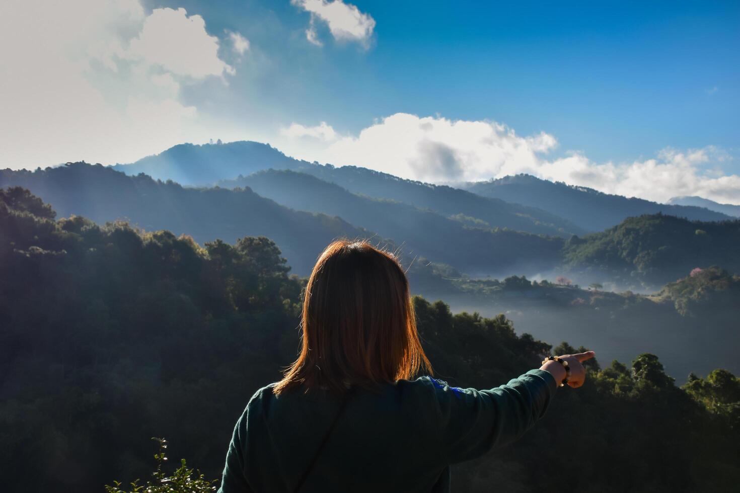 A woman is standing on a mountain overlooking the valley photo