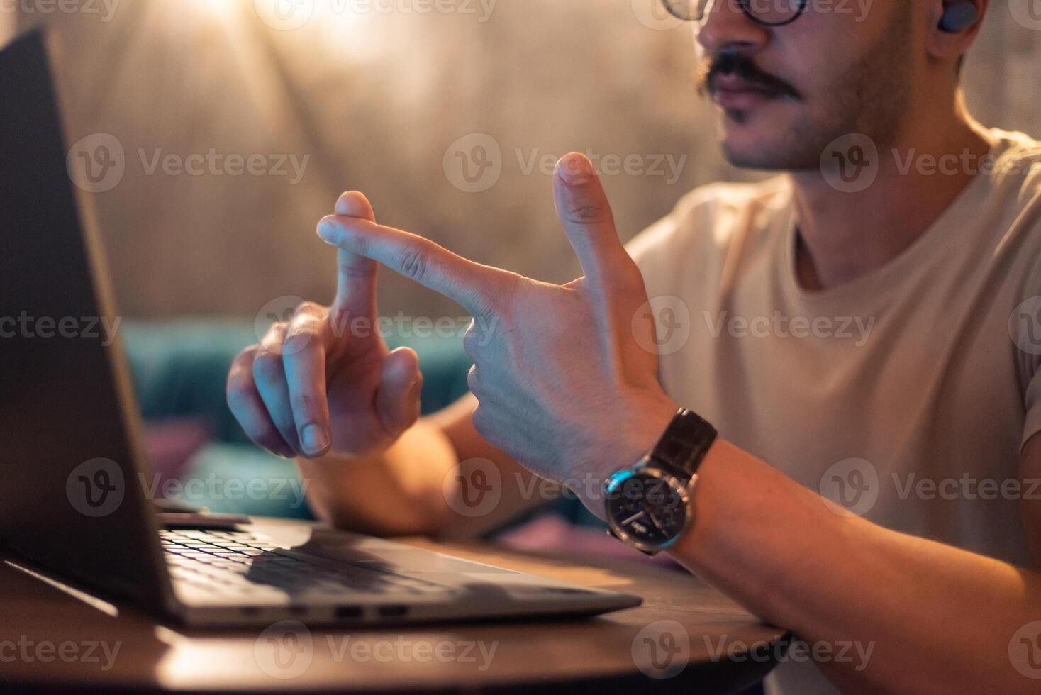 Close cropped image of a young man working in a modern interior with ambient light, having a conference meeting on a laptop, concept of remote work or online learning. photo