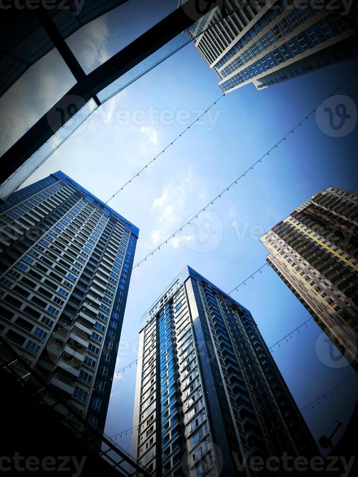Photo of tall modern buildings standing against a bright blue sky, ideal for urban landscape, city architecture, business district, and travel related themes