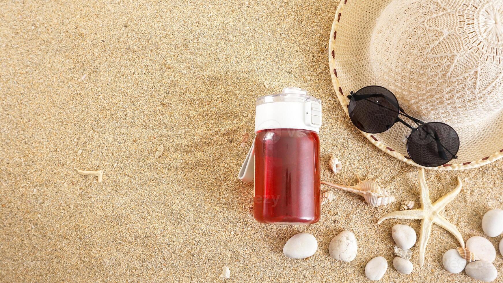 Top view flat lay of summer hat, sunglasses, a drink tumbler, and ocean animals isolated on beach sand background photo