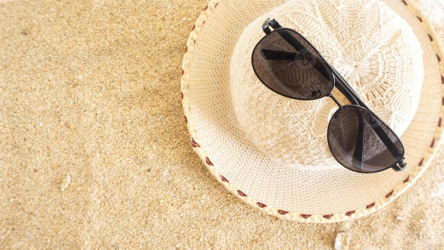 Top view flat lay of summer hat and sunglasses isolated on beach sand background photo