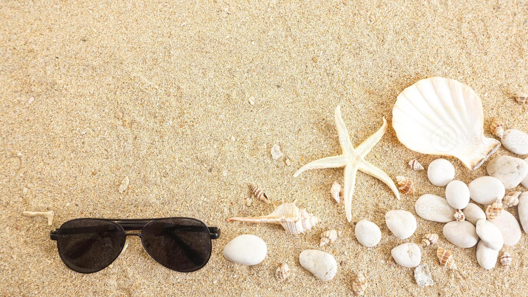 Top view of flat lay composition with sunglasses, starfish, and seashells isolated on beach sand background photo