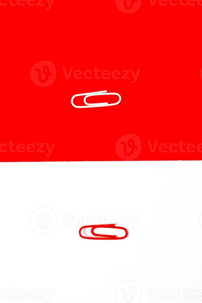 Two paper clips on divided red and white backgrounds offering a contrasting visual statement photo