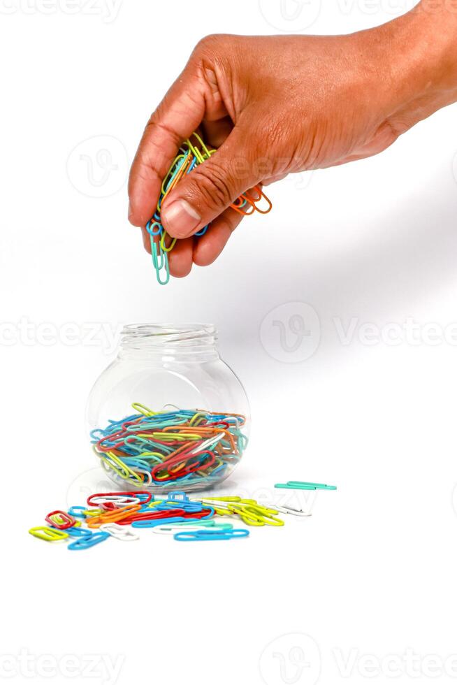 Hand placing colorful paper clips into a jar, symbolizing organization and office supplies for a creative workspace photo