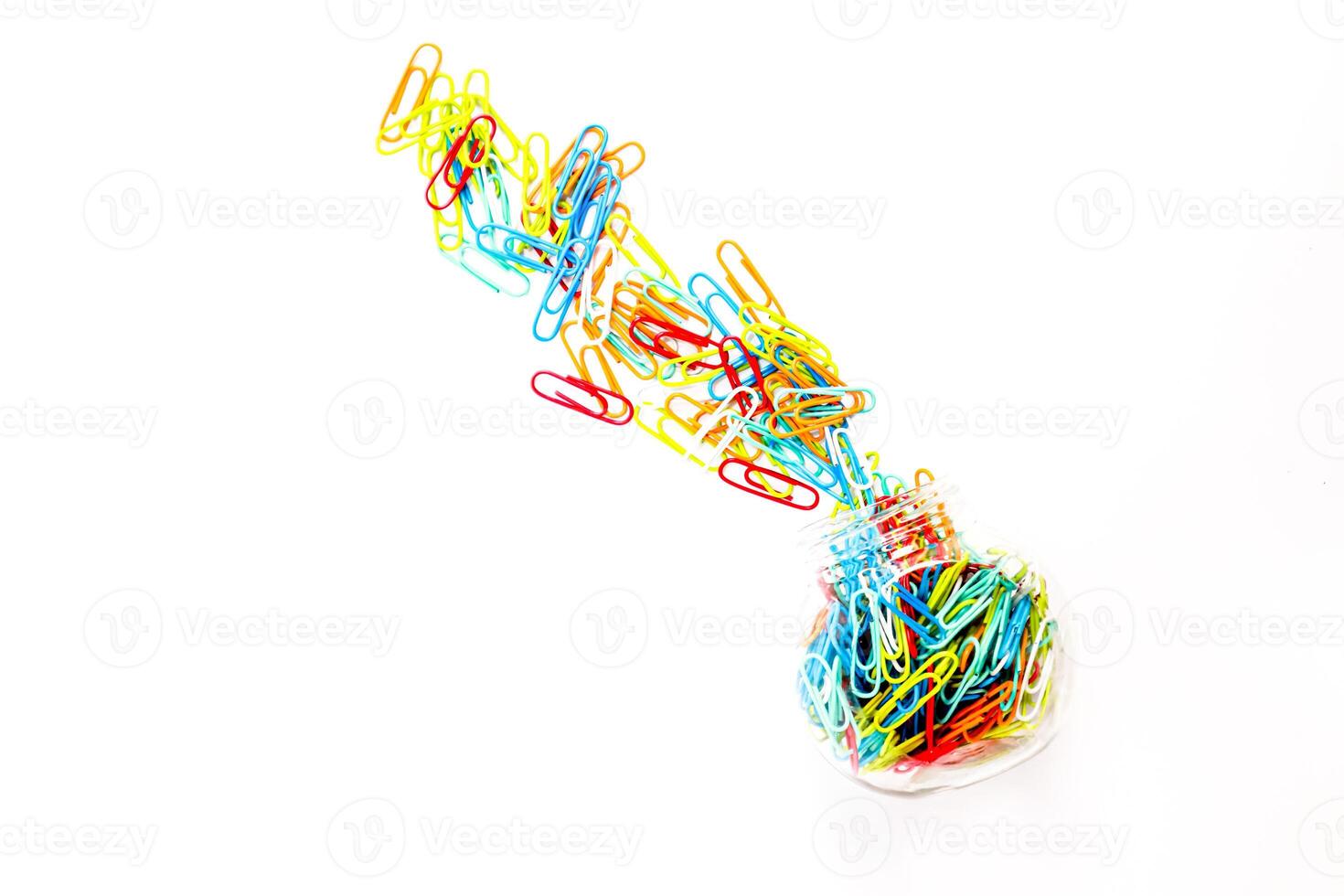 Colorful paper clips spilling from a jar, isolated on white, symbolizes creativity photo