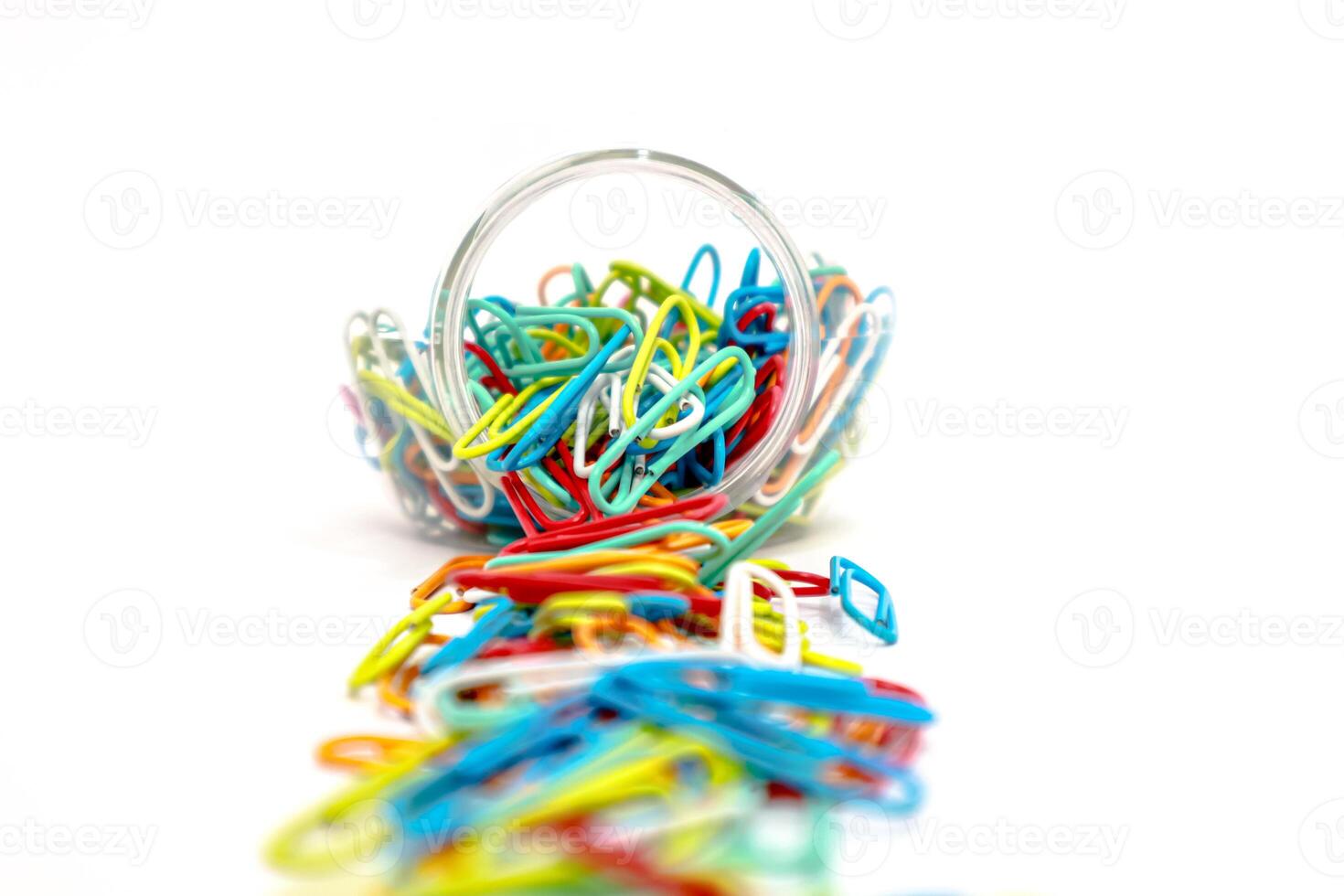 Colorful Paper Clips Spill from a Clear Container on a White Background photo