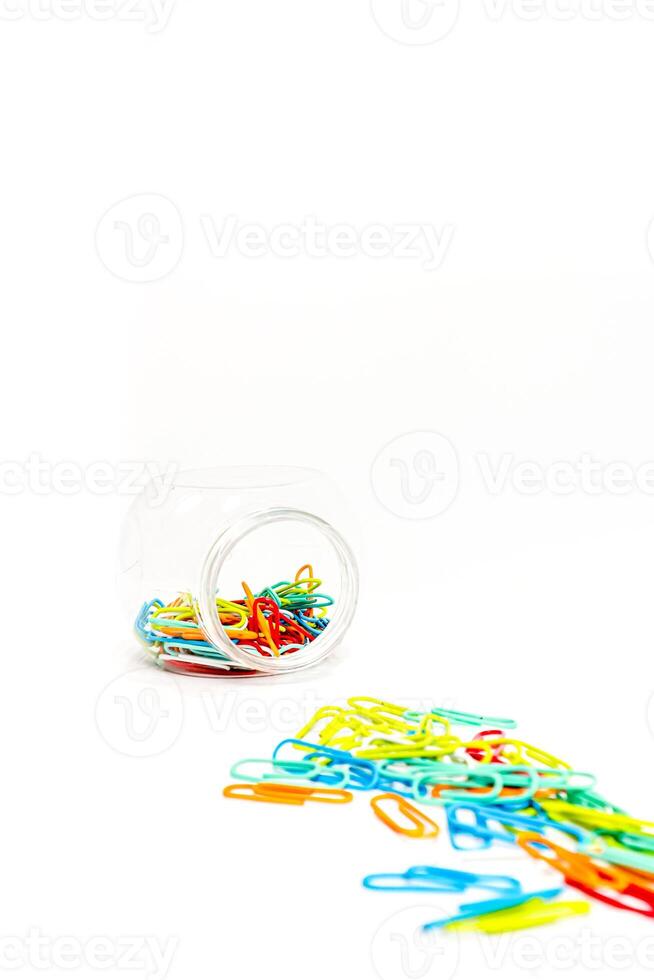 Vibrant Multicolored Paper Clips Spill from Clear Container on White Background photo