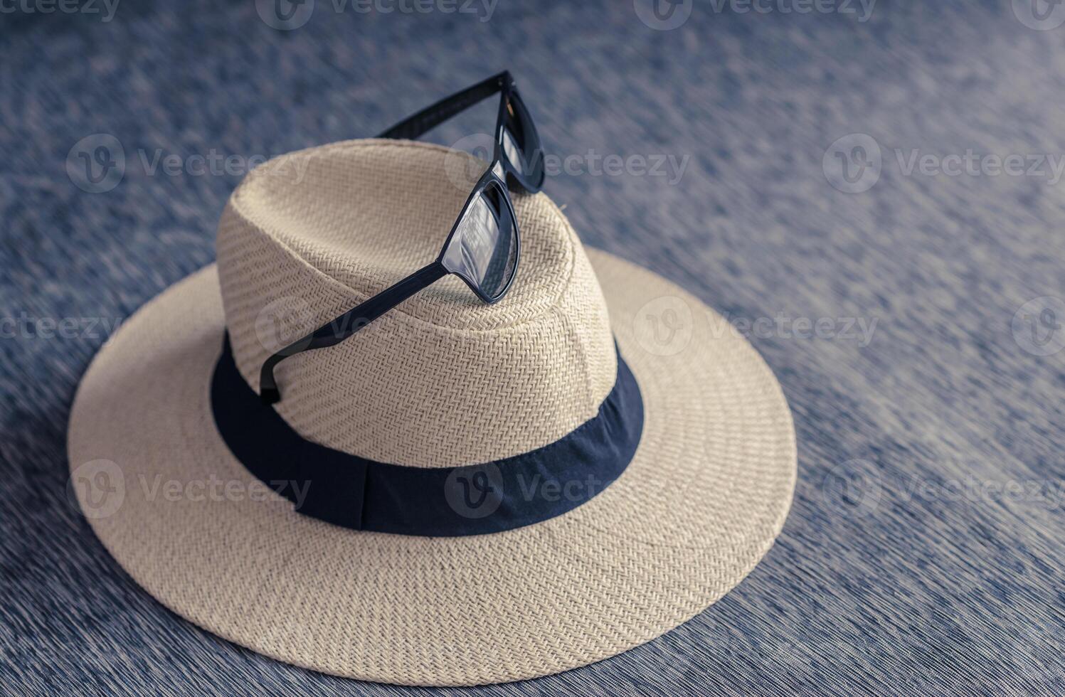 straw hat with black ribbon and sunglasses on sofa wtih free space. vacation travel in summer concept. photo
