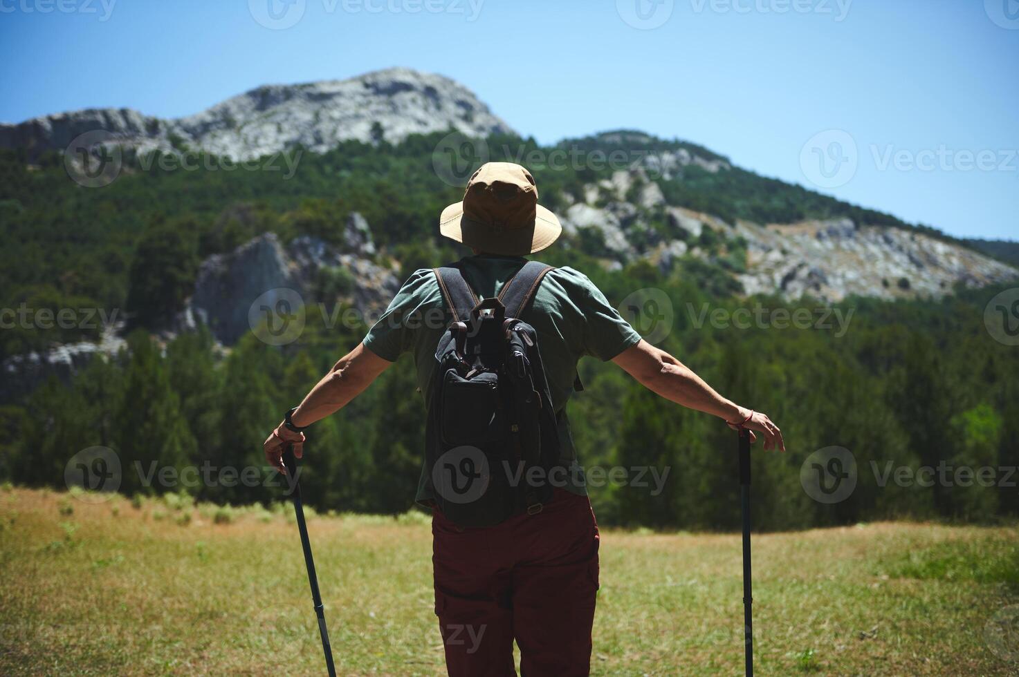 Man Hiking in Rugged Mountain Terrain on a Sunny Day photo
