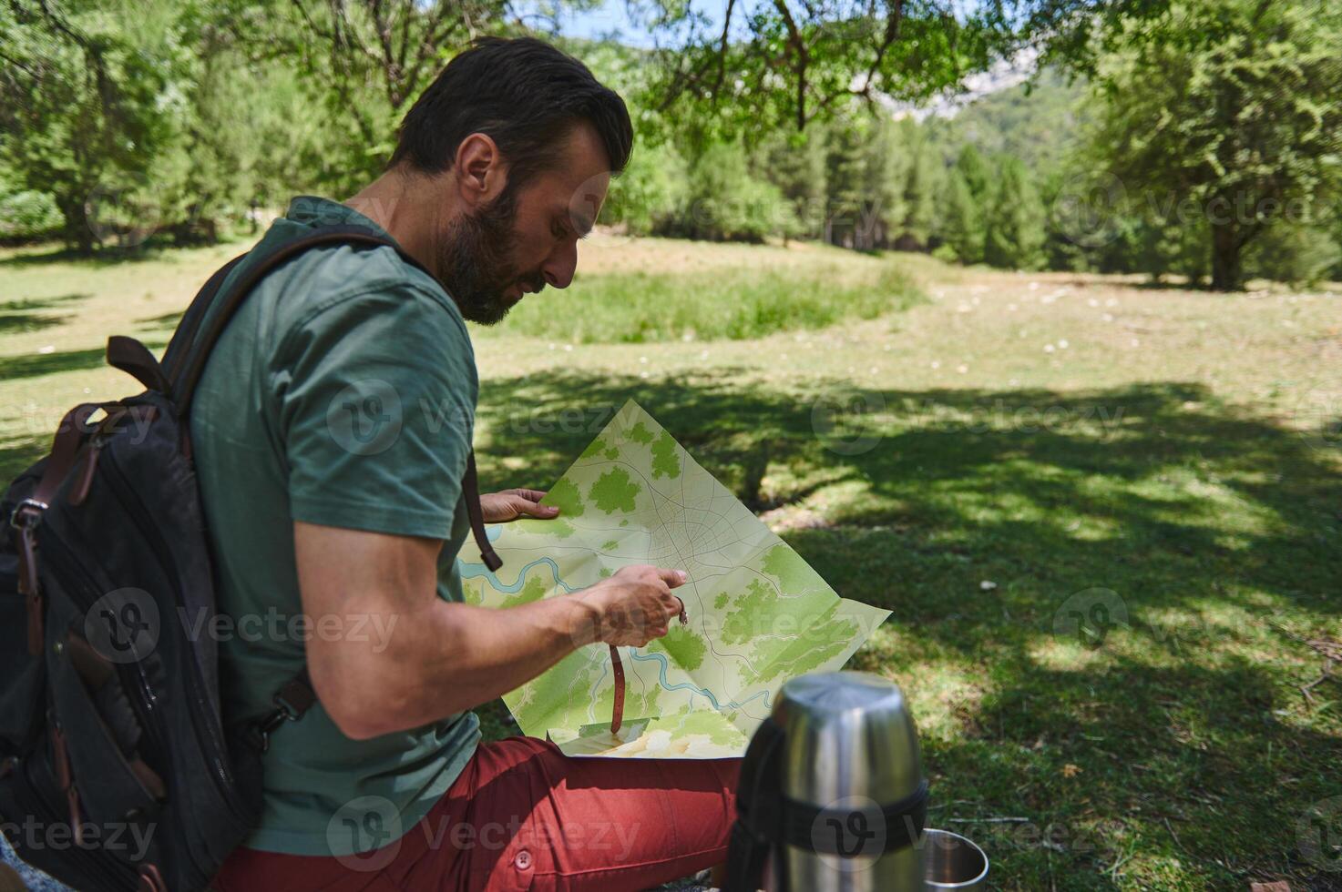 Bearded Man Exploring Nature with a Map in a Forest on a Sunny Day photo