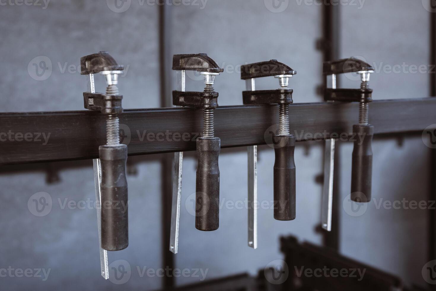 Four black clamps mounted on a metal rack on the construction site. The clamps are designed for holding materials securely in place photo