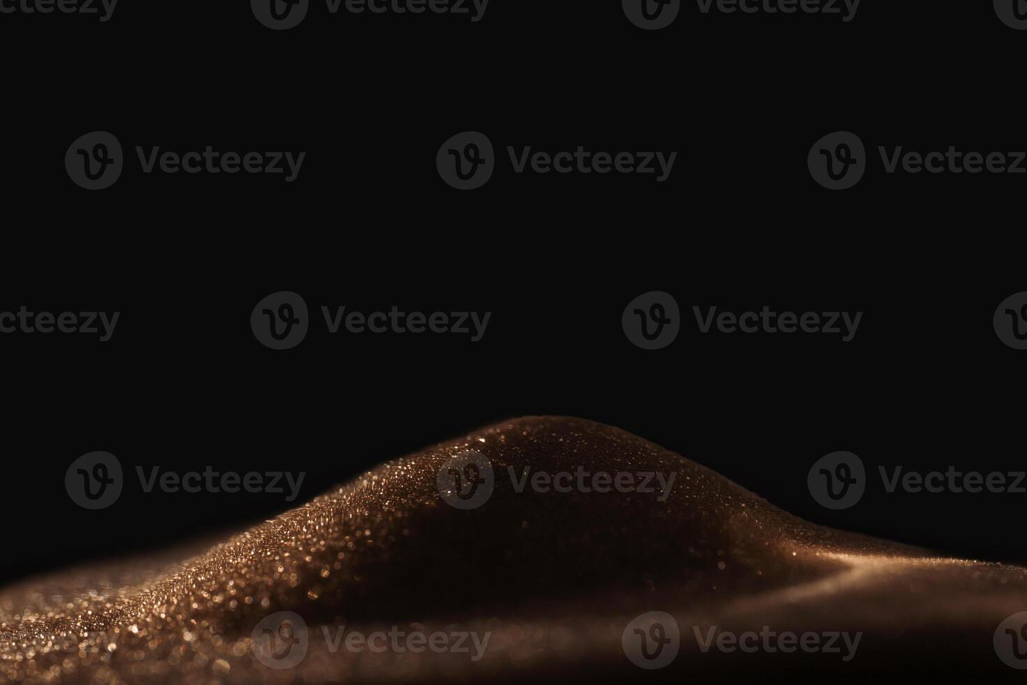 Gold sparkly hourglass sand on black background. Minimalist low key poto for concepts of time, travel to the desert photo