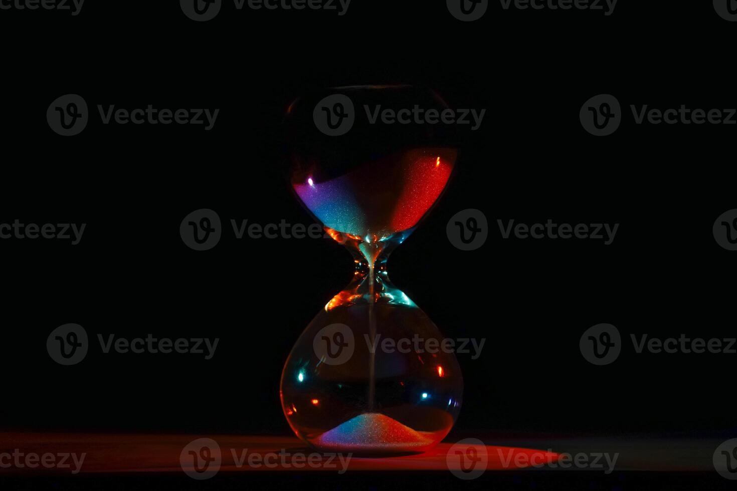 artistic glowing neon hourglass, symbolizing time and creativity. Vibrant lighting against a dark minimalist backdrop. Concepts of time management, life balance, and artistic design. photo