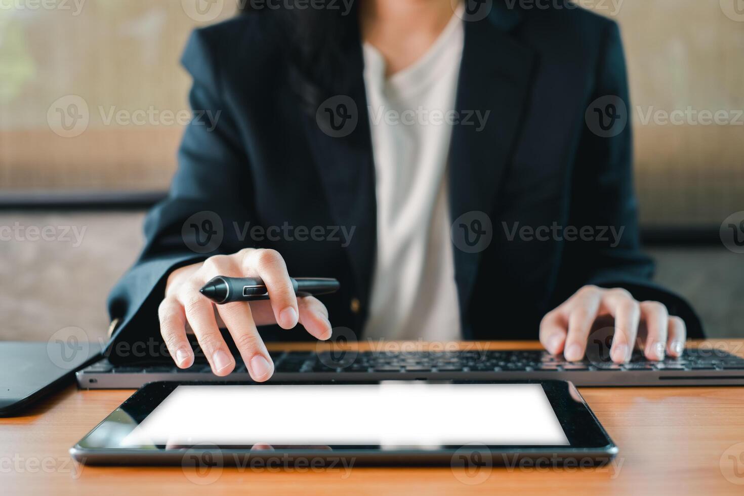 A business professional multitasking with a tablet and laptop, showcasing modern technology in a work environment. photo