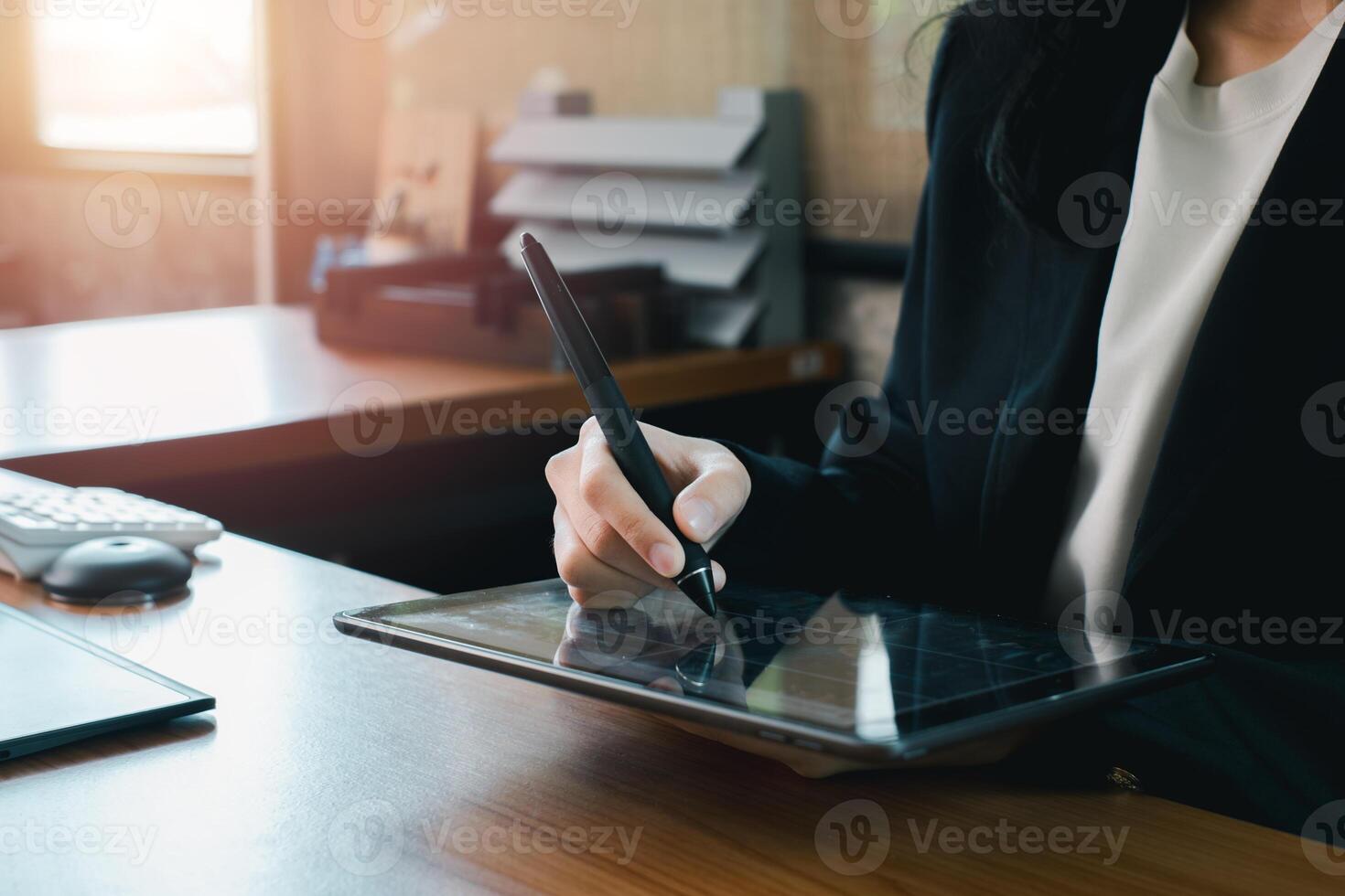 Businesswoman using a digital tablet with a stylus in a modern office environment, emphasizing technology and productivity. photo