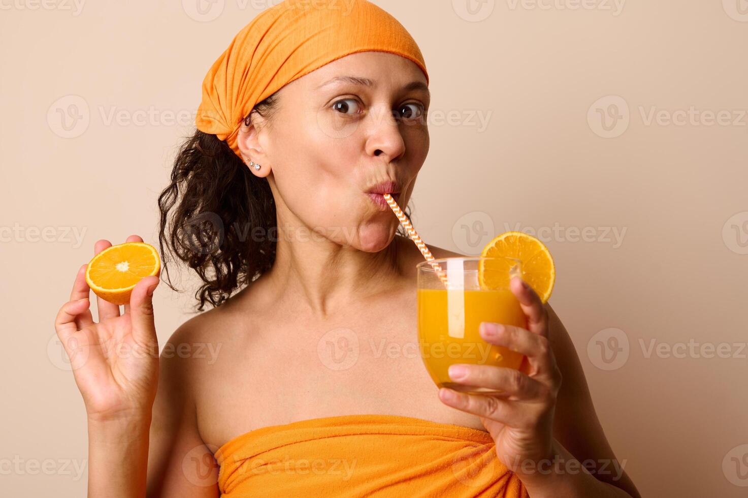Refreshing Portrait of a Woman Enjoying Orange Juice While Holding Fresh Orange Slices photo