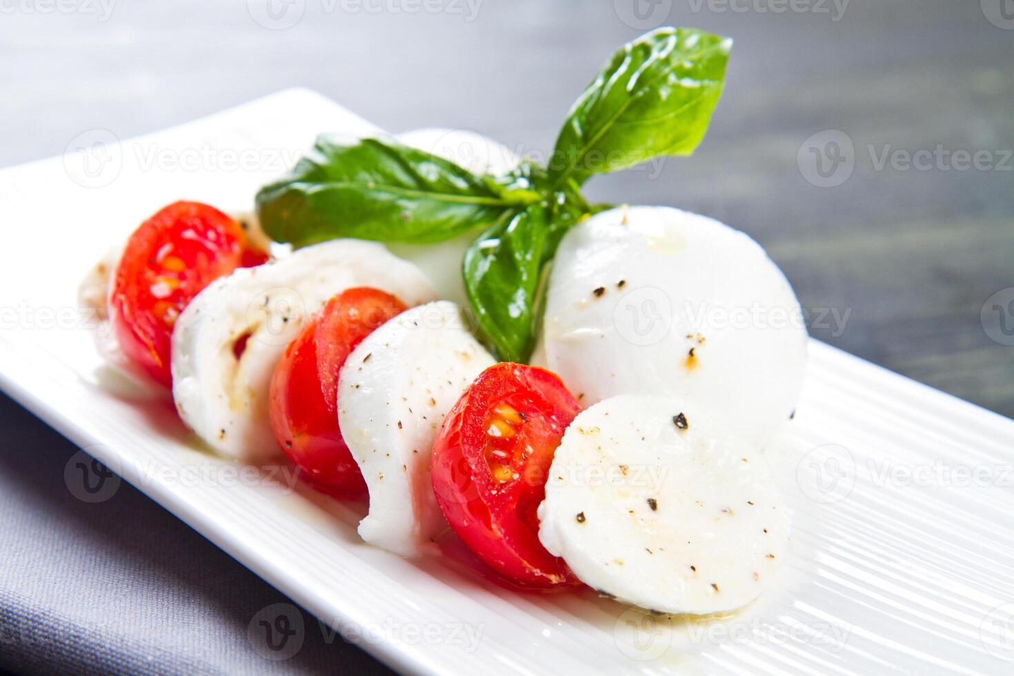 Tomato and mozzarella with basil leaves photo