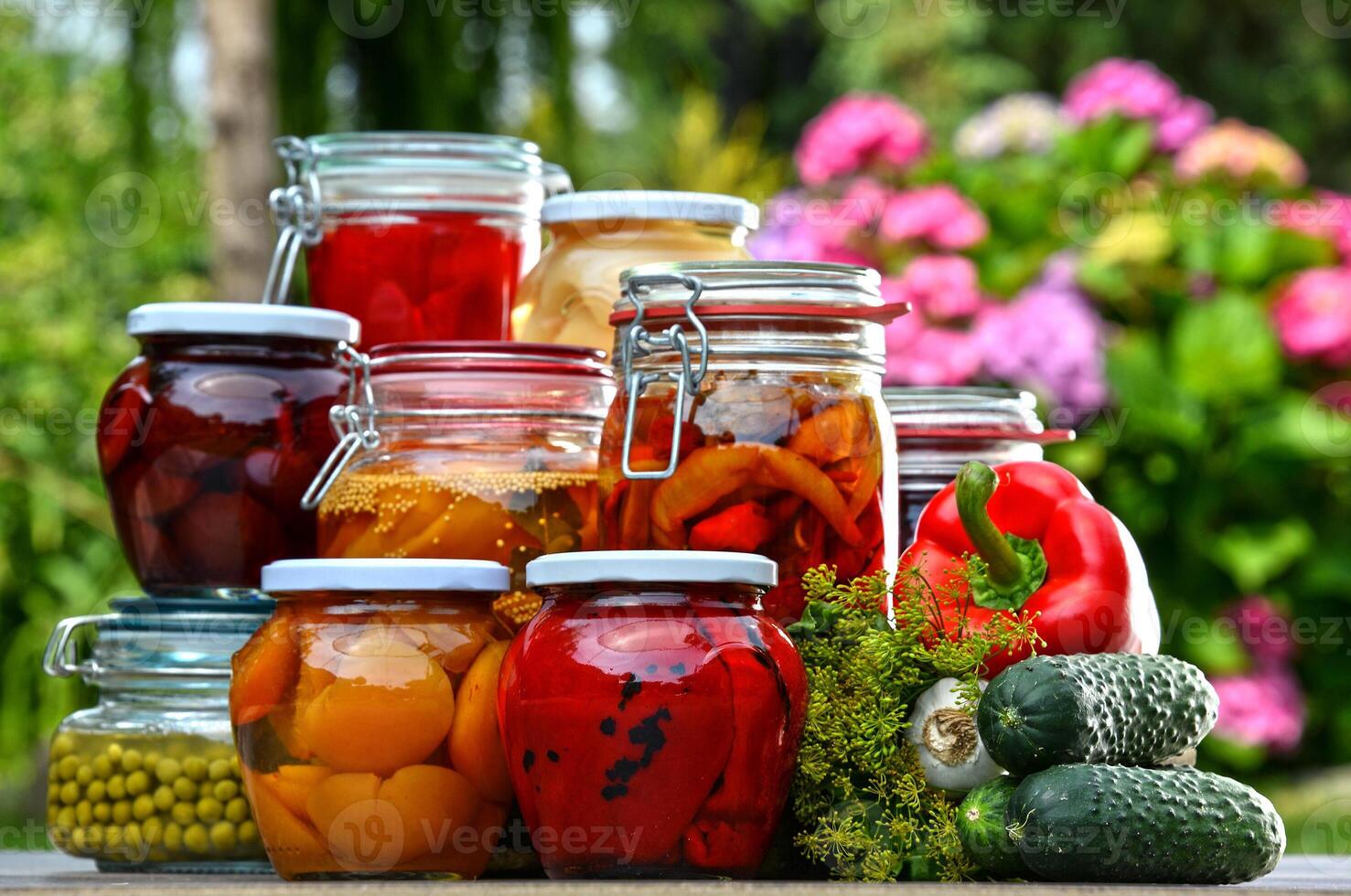 Jars of preserved vegetables in garden photo