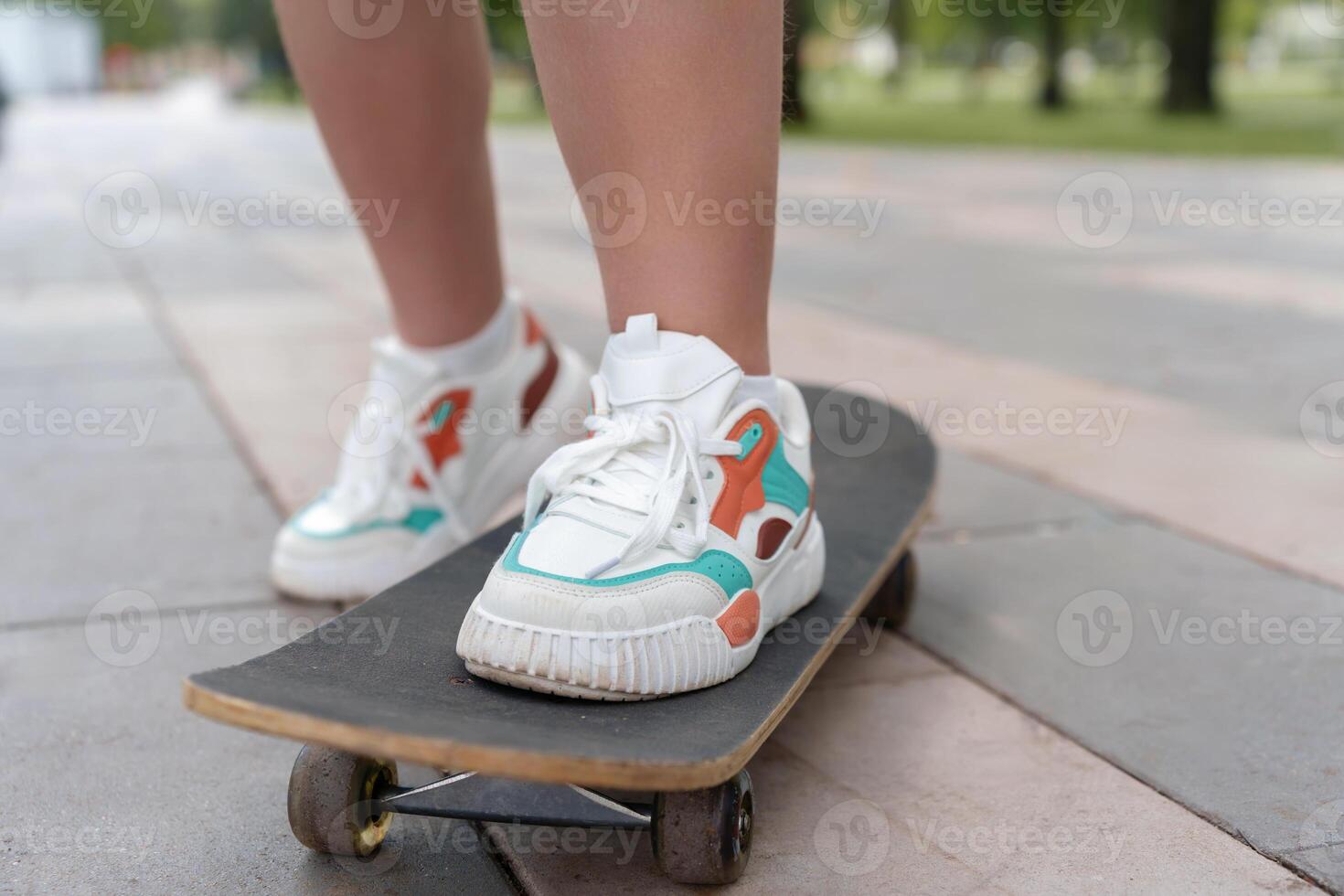 Close-up of a teenager's feet in light, casual sneakers firmly planted on a skateboard, exuding a sense of confidence, freedom, and the spirit of summer photo