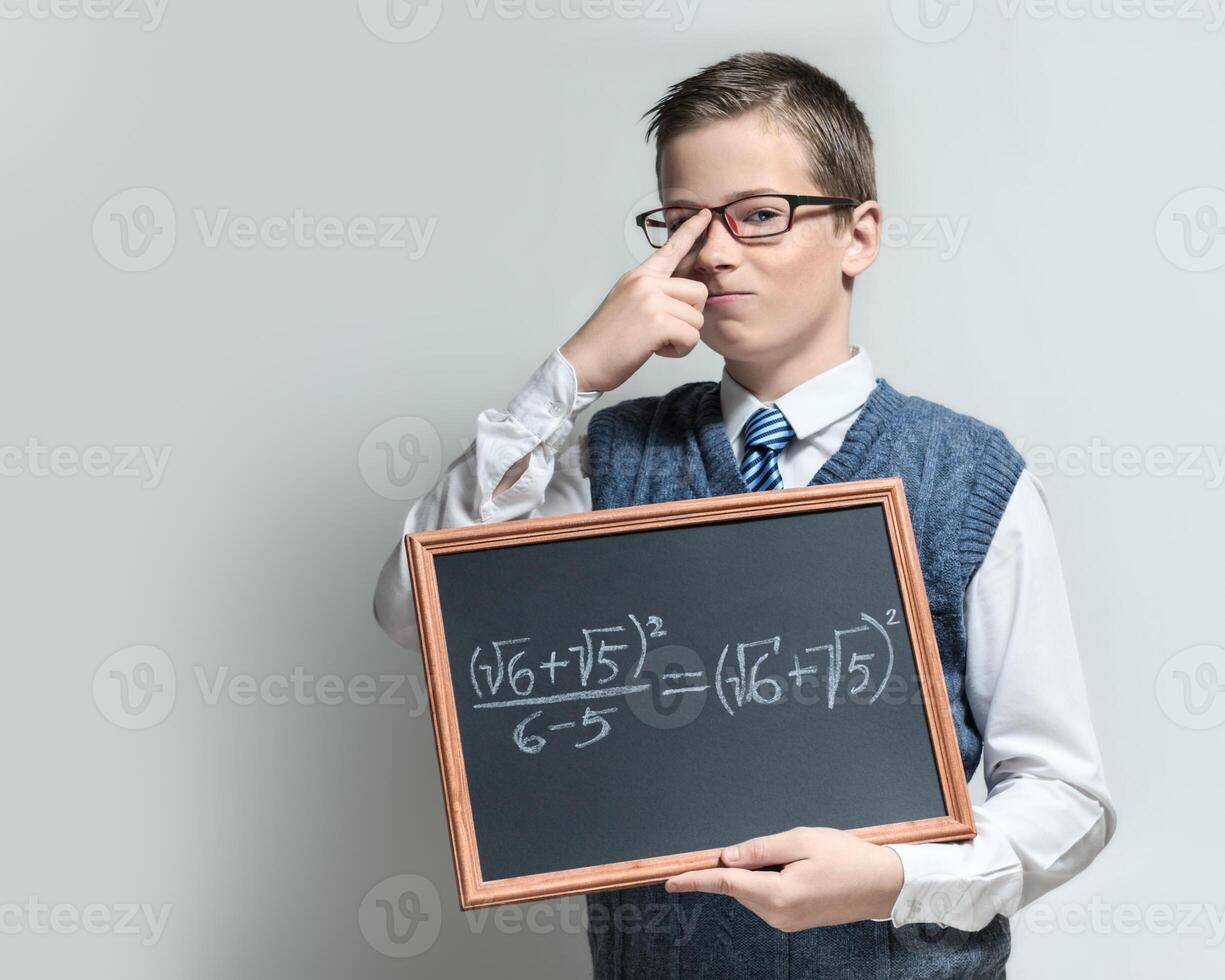 Clever schoolboy in glasses with mathematical equation photo