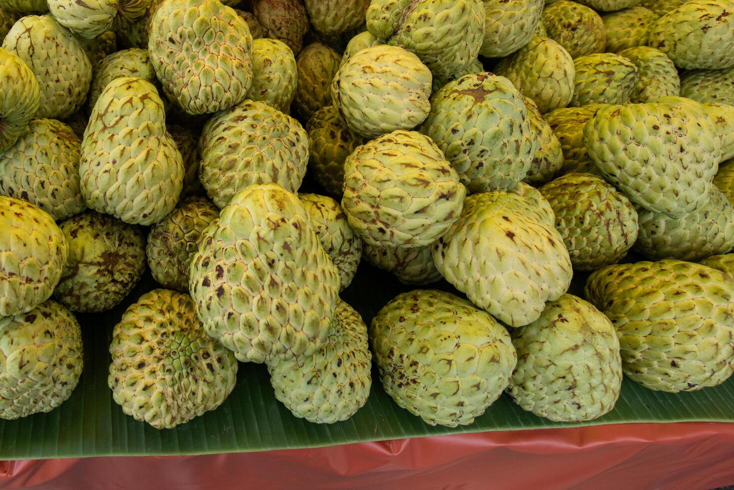 custard apple piled up on banana leaves photo