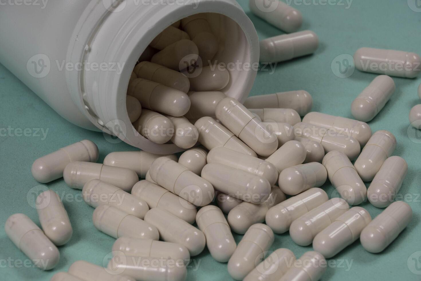 One bottle of pills, some of which spilled into a light blue surface photo