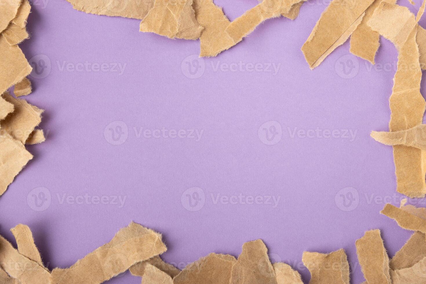 Brown torn craft paper strips frame on purple surface background photo