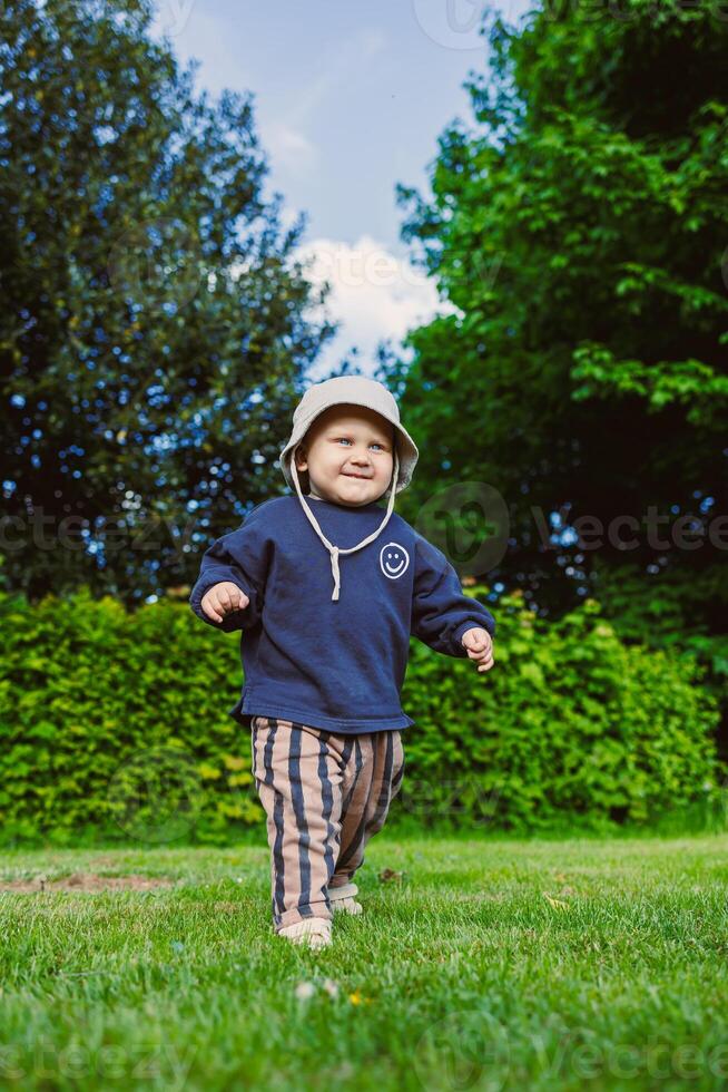 A joyful toddler is happily exploring the wonders of nature in a bright, sunny outdoor setting filled with greenery and playful vibes, showcasing the essence of childhood and carefree adventure photo