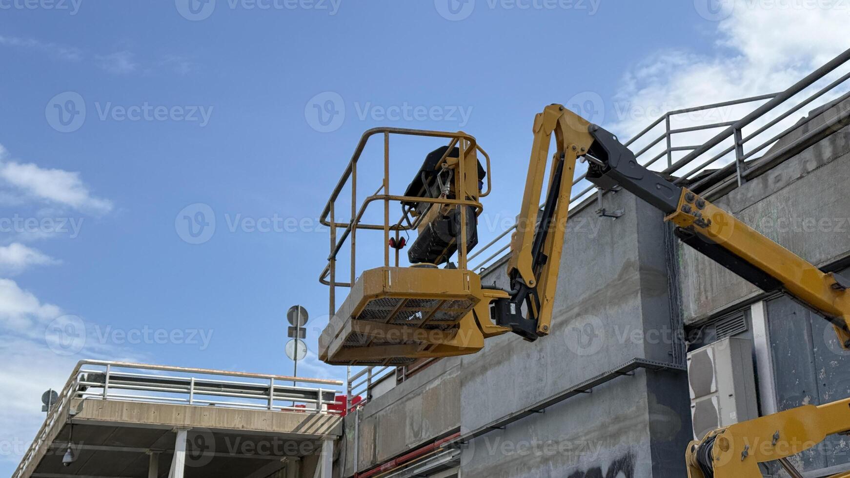 A determined South Asian male worker operates a cherry picker under the azure sky, embodying Labor Days industrious spirit photo