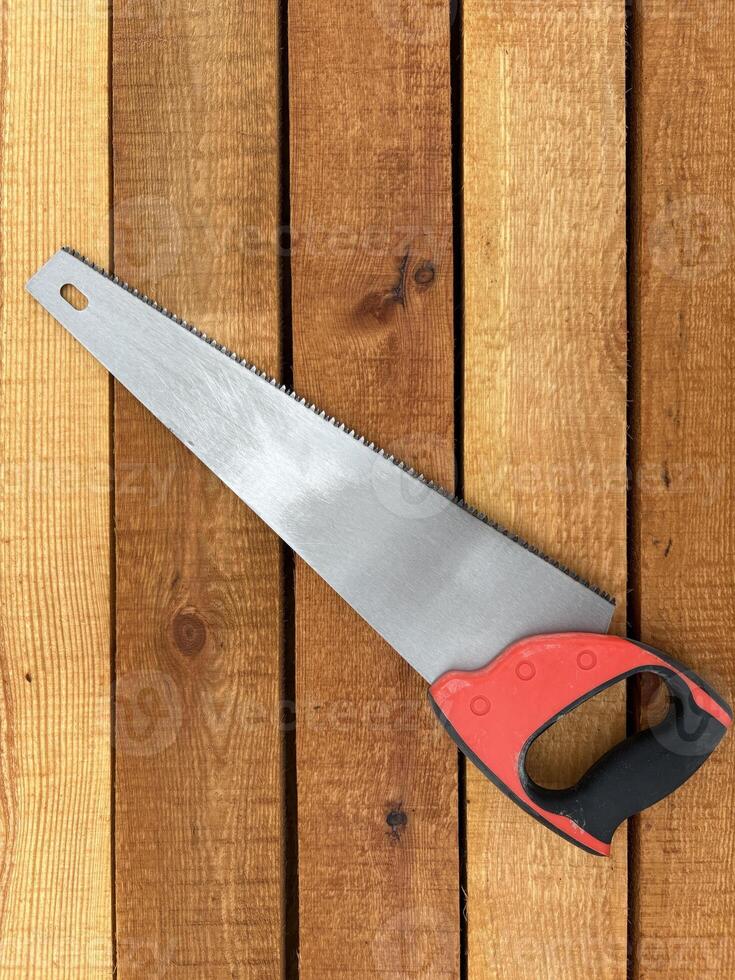 A handsaw rests on stacked wooden boards with detailed grain patterns, ready for use. photo