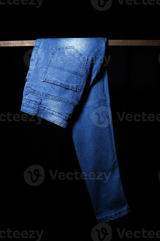 Blue Jeans hanging Isolated on Black Background photo