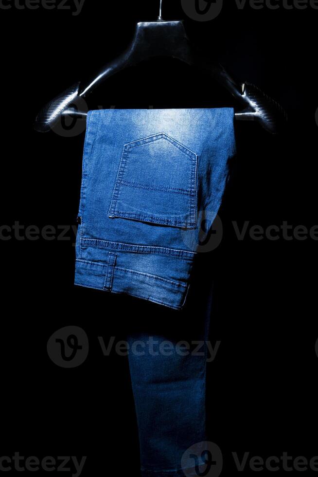 Blue faded Jeans on Hanger, Isolated on Black Background photo
