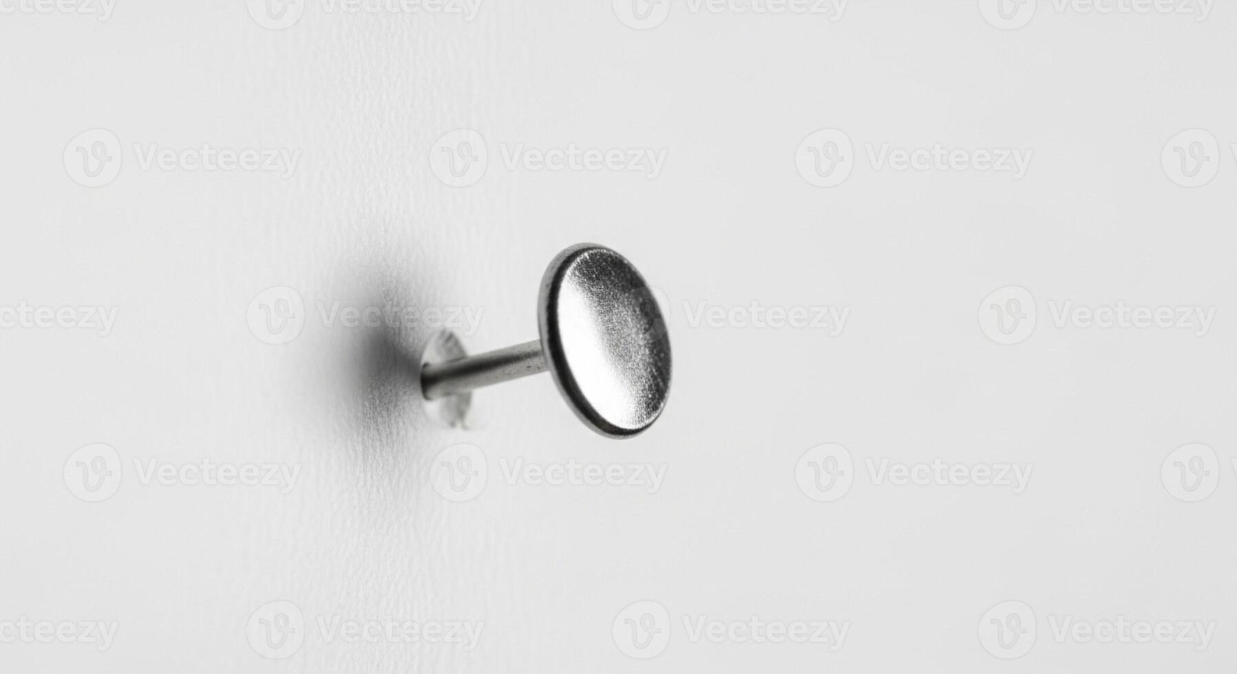 Closeup of a thumb tack stuck in a white surface photo