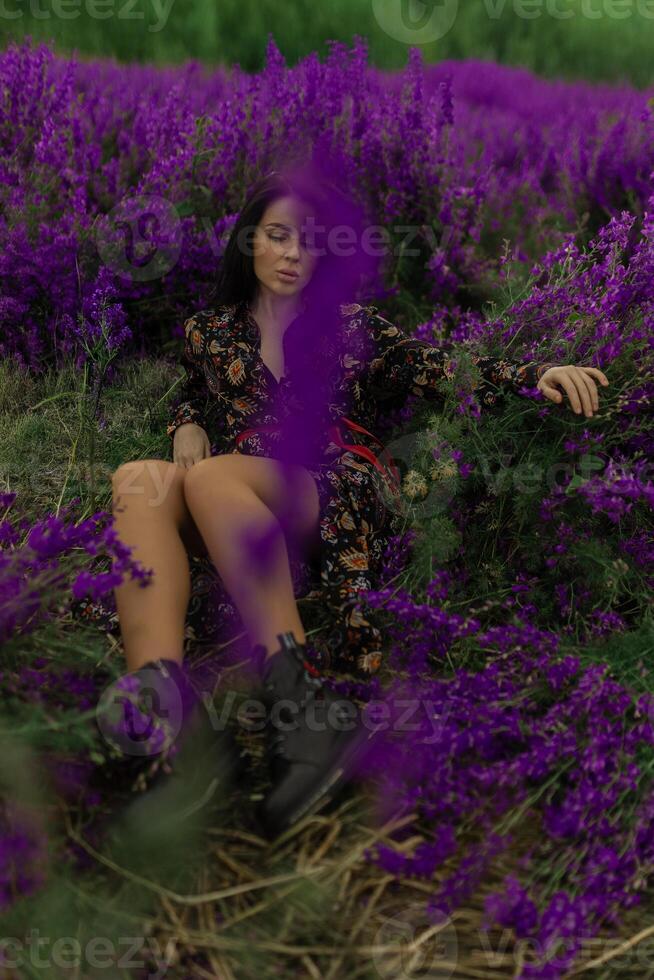 Brunette woman relaxing in a field surrounded by vibrant delphiniums during a sunny day in a beautiful natural setting photo