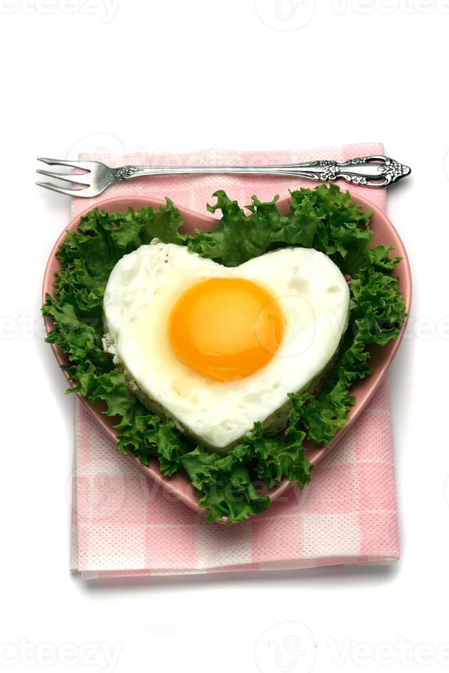 A heart shaped egg in a plate with a fork photo