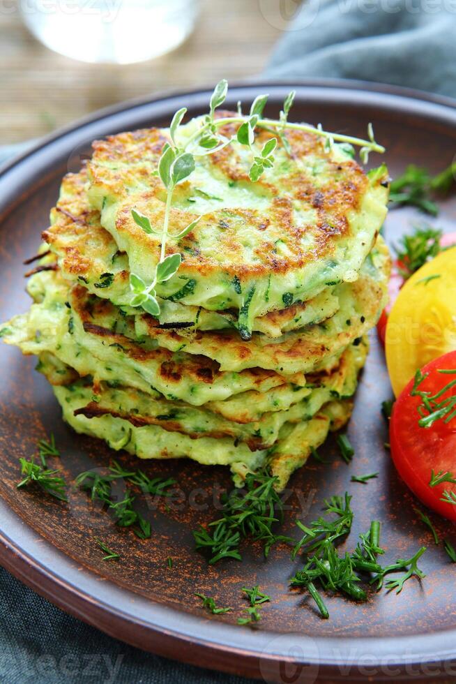 A plate of food with a tomato and a green vegetable photo