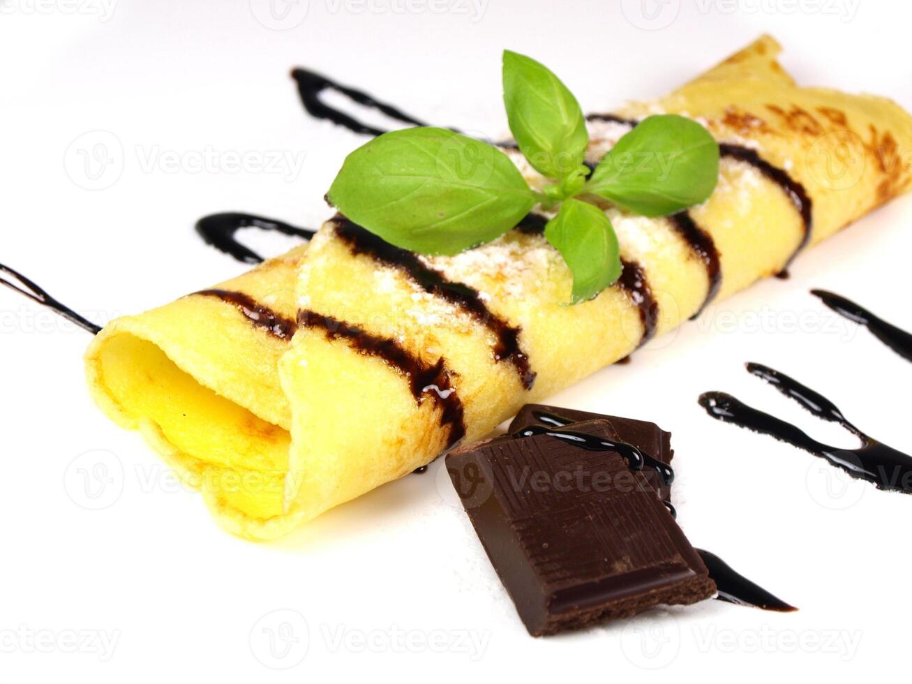 A chocolate crepe with a chocolate sauce and a piece of basil photo