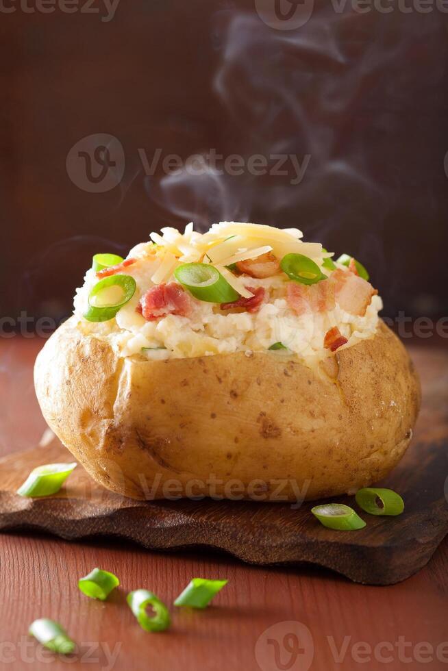 A baked potato with cheese and green onions photo