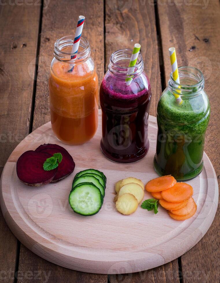 A wooden table with four jars of juice on it photo
