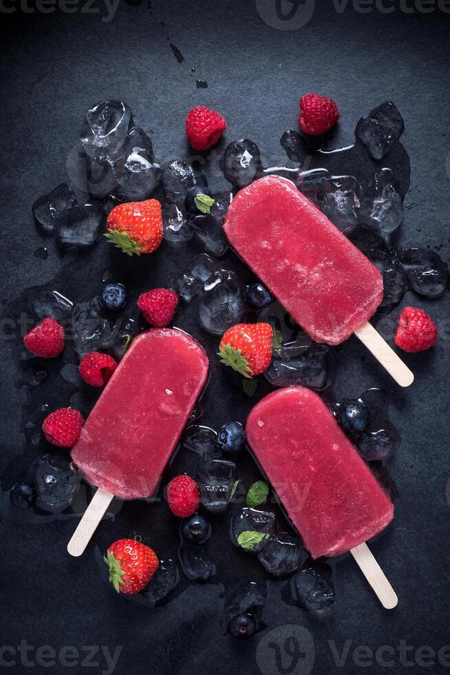 Popsicles with berries and ice on a black background photo