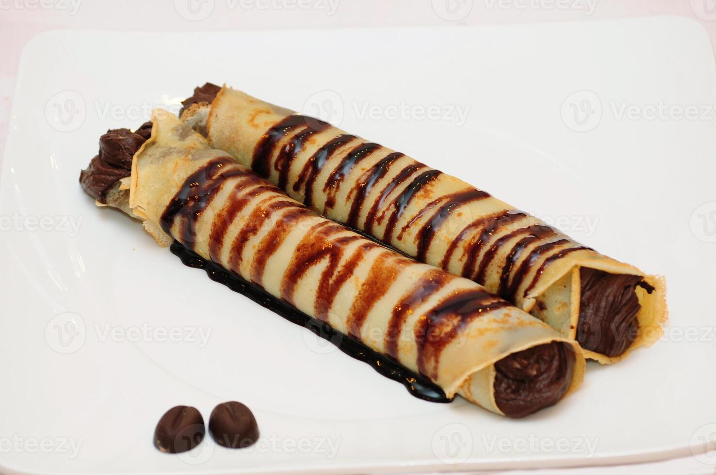 A plate with two rolls of chocolate covered pastry photo