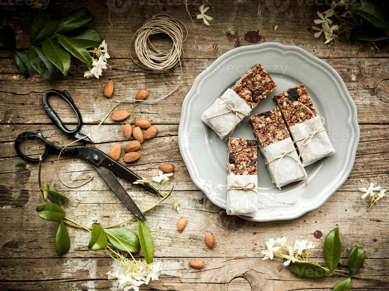 Granola bars and almonds on a plate on a wooden table photo