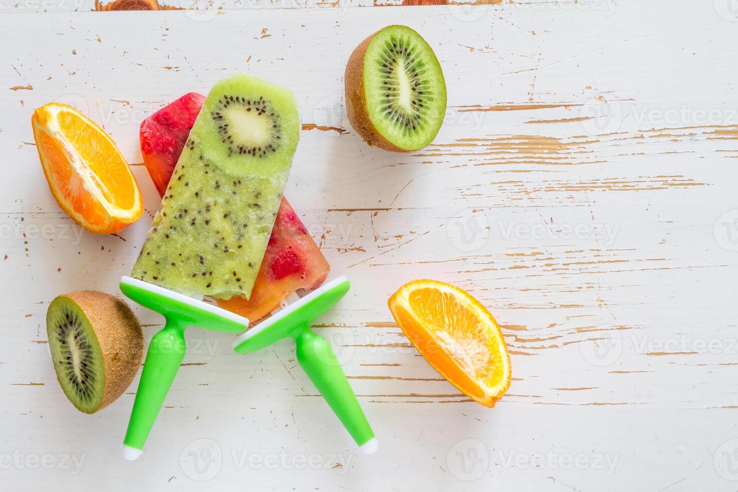 A bunch of fruit and a popsicle on a white table photo